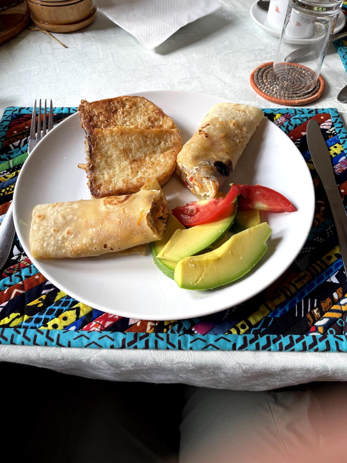 Breakfast at Gorilla Bluff Lodge in Buhoma — avocado, rolex wrap, and French toast on a colourful African cloth