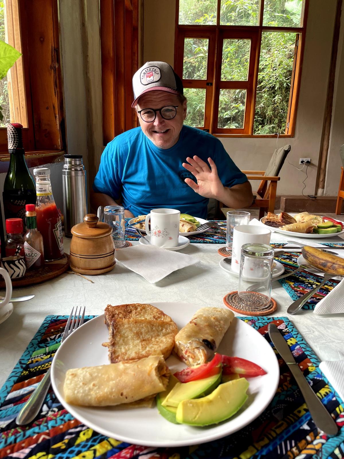 Breakfast plate at Gorilla Bluff Lodge in Buhoma — avocado, chapati wraps, and french toast on colourful African cloth