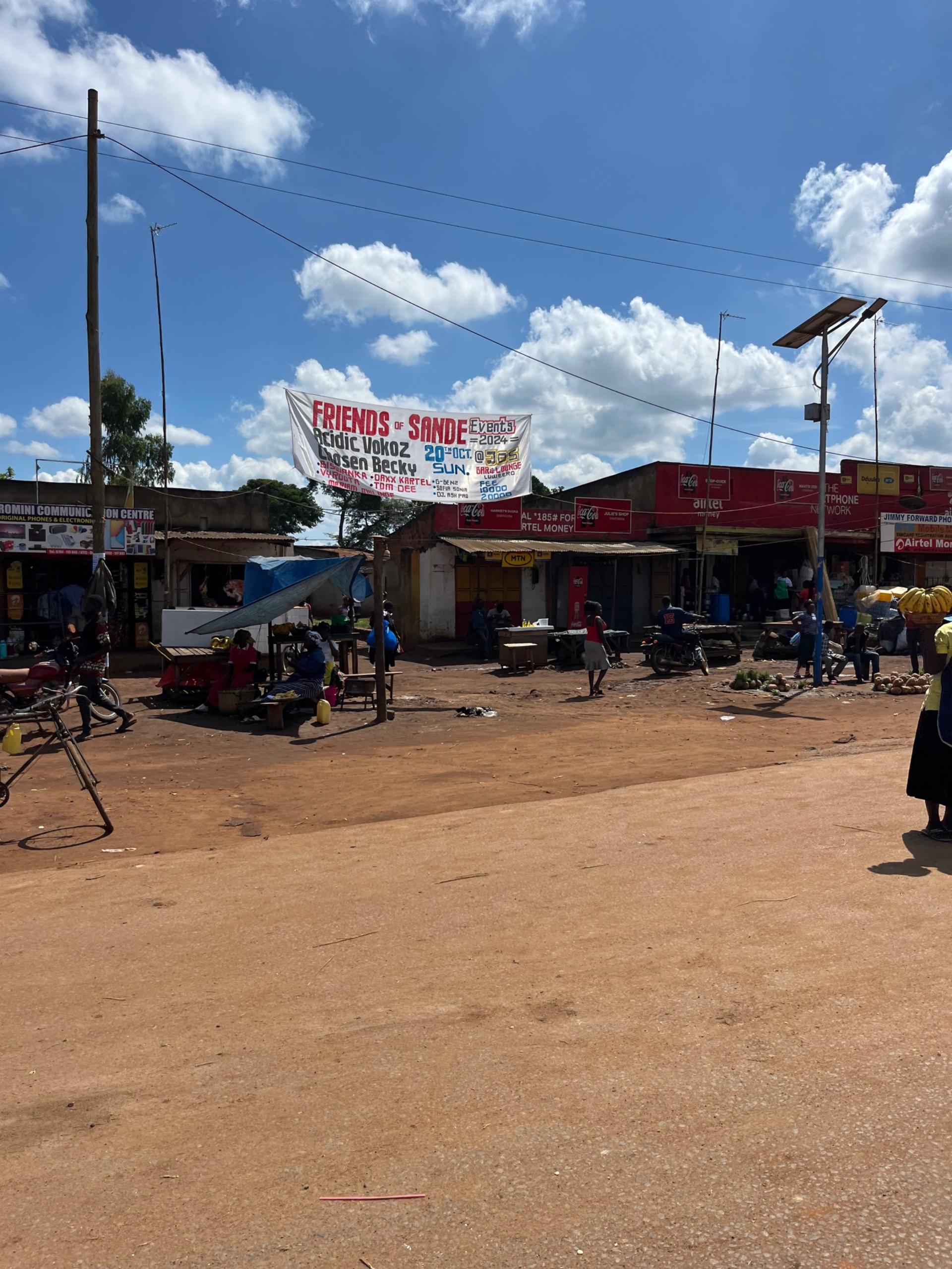 Marketplace in Luwerro on the Kampala Road — small trading stalls with corrugated iron roofs along a dusty square